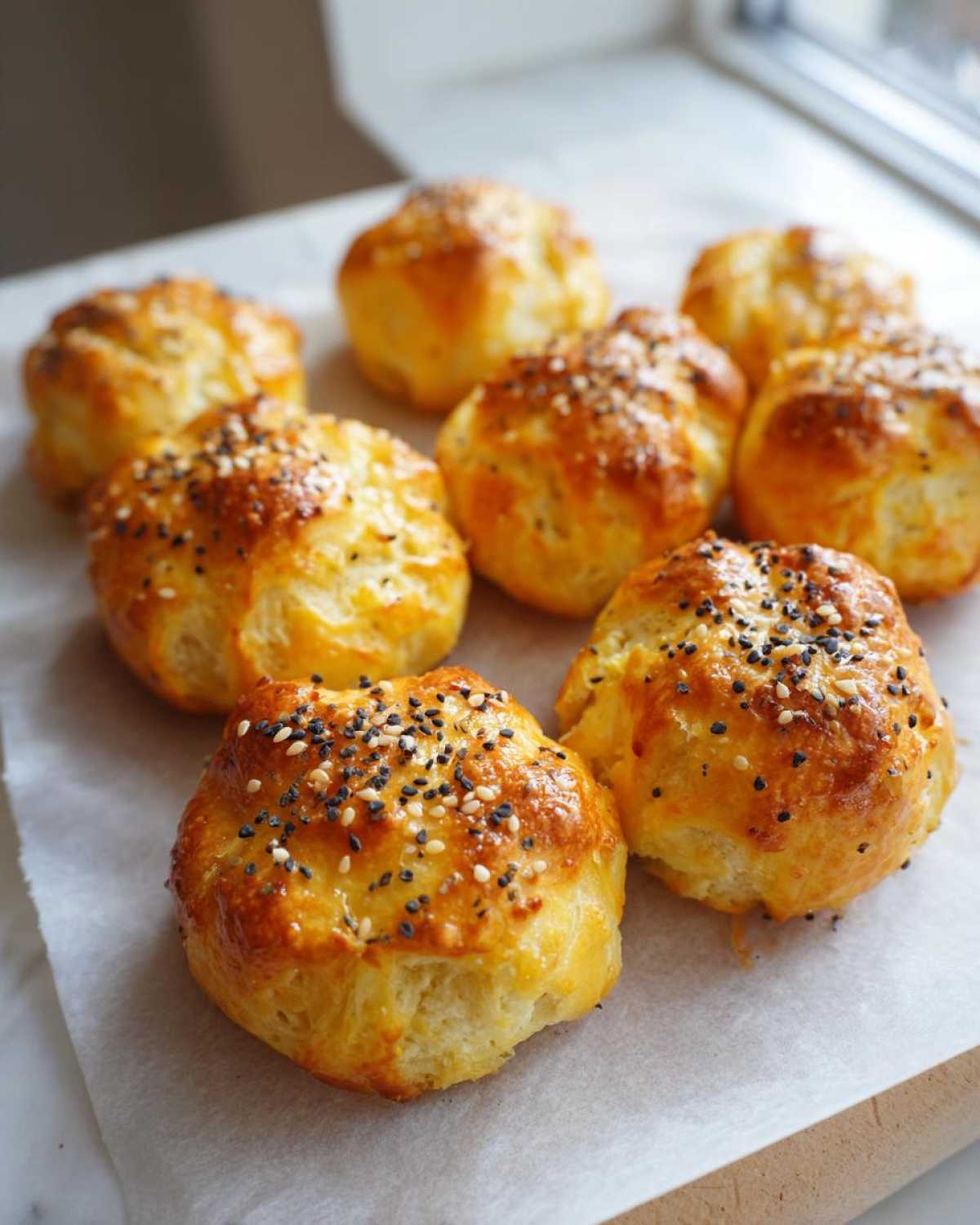 Eight golden-brown High-Protein Cottage Cheese Bagel Bites topped with everything bagel seasoning, resting on parchment paper.