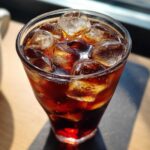 Close-up of a tall glass filled with Iced Cherry Vanilla Cold Brew and large ice cubes.