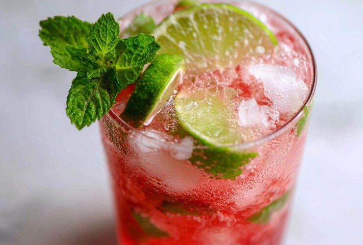 Close-up of a vibrant Iced Watermelon Lime Cooler filled with crushed ice, lime slices, and garnished with fresh mint.