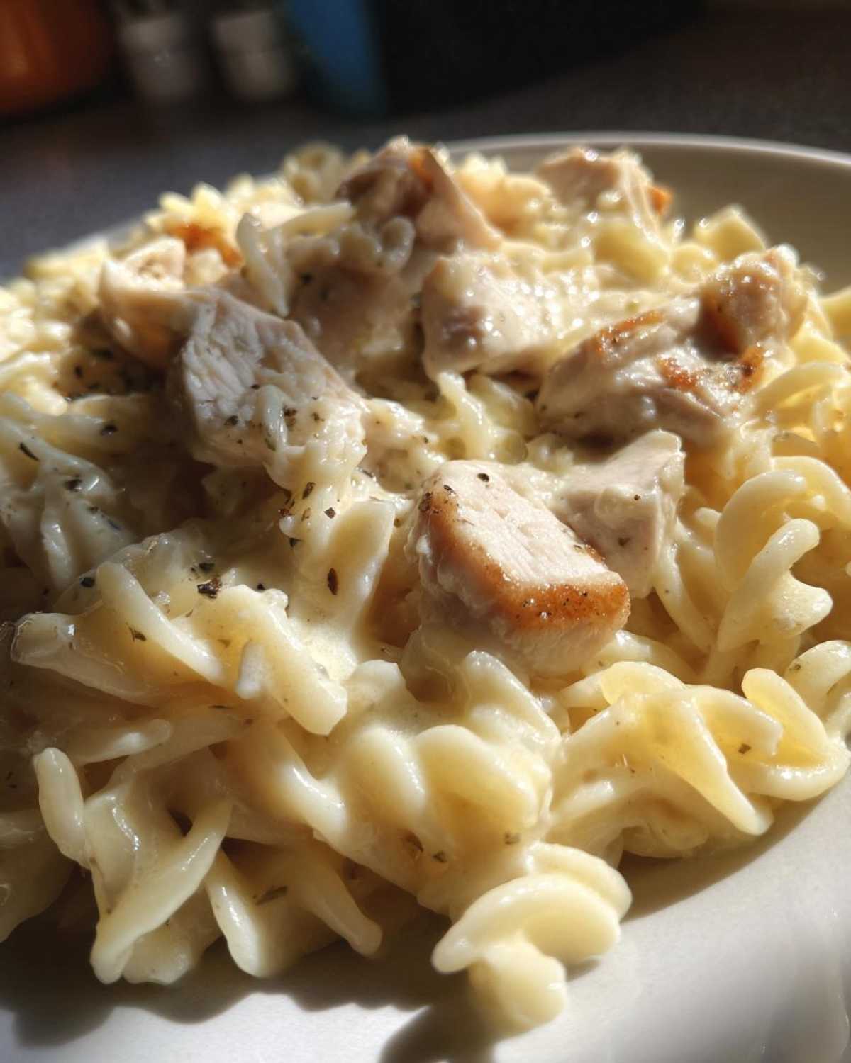 Close-up of a creamy pasta dish featuring pieces of seared chicken mixed with rotini pasta in a rich sauce, Instant Pot Creamy Chicken and Orzo.