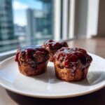 Three perfectly cooked mini meatloaf portions topped with a thick, glossy brown glaze, served on a white plate.