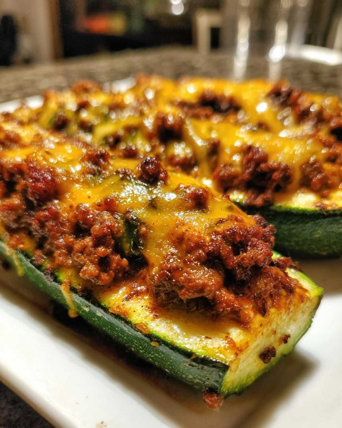 Close-up of Keto Cheesy Taco Stuffed Zucchini Boats topped with seasoned ground meat and melted cheddar cheese.