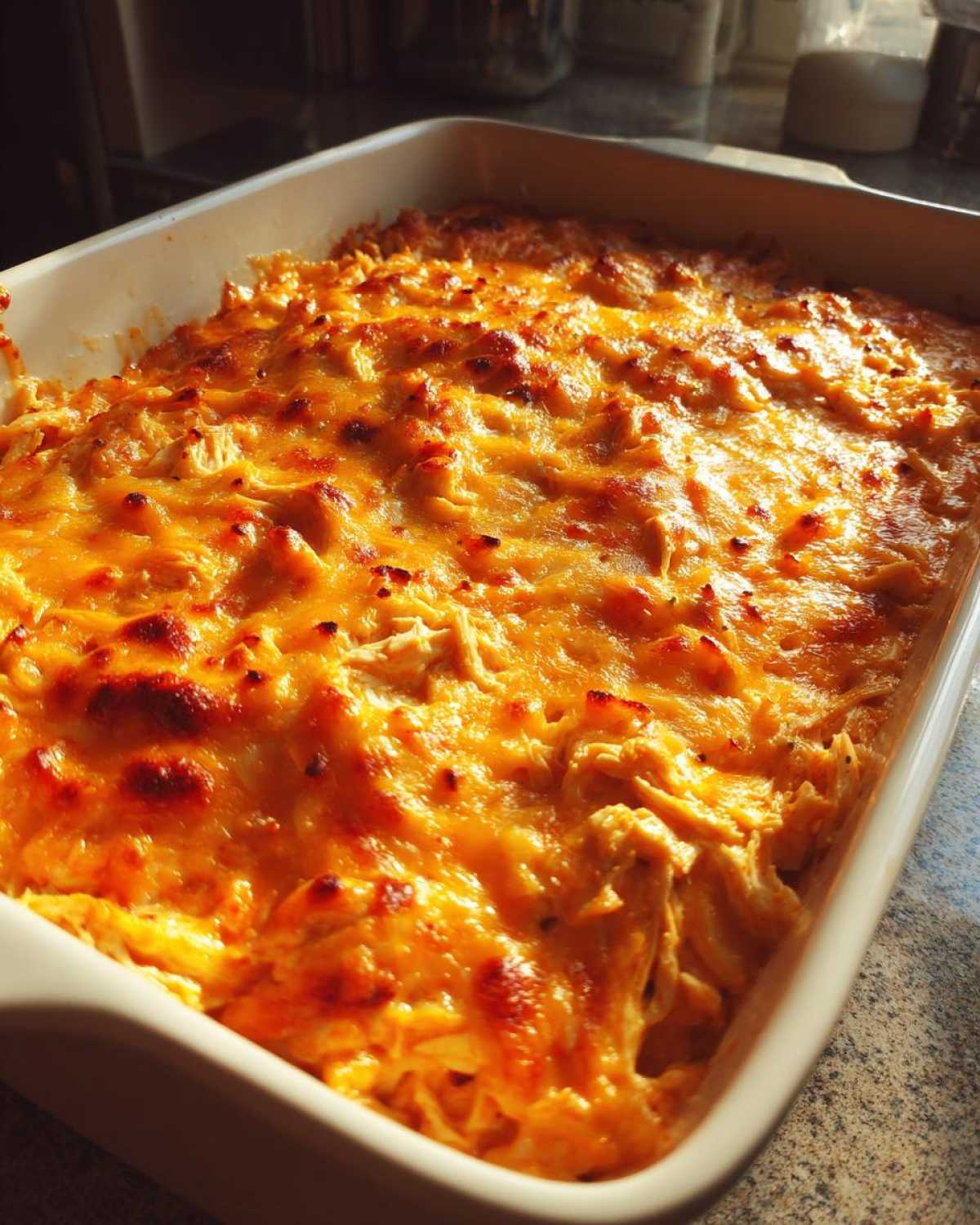 A bubbling, golden-brown baked Keto Creamy Buffalo Chicken Casserole topped with melted, slightly charred cheese.
