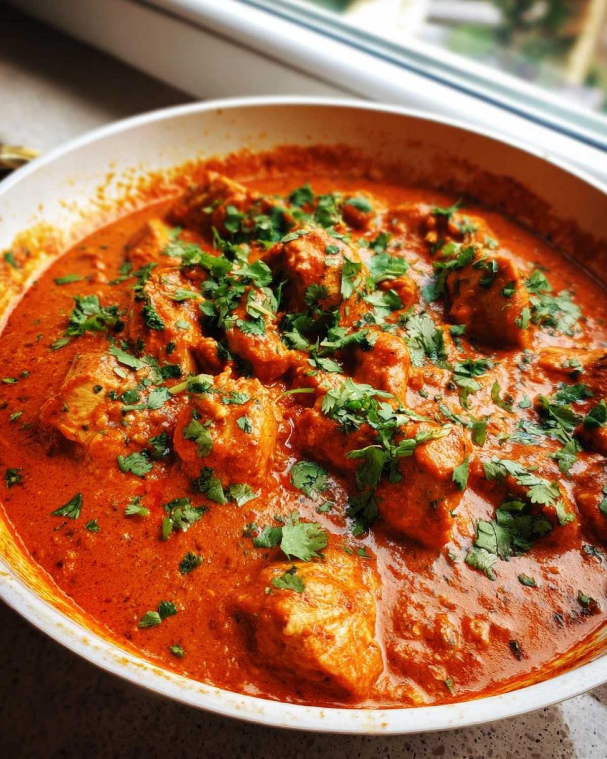 Close-up of rich, orange-red Keto Creamy Butter Chicken Skillet garnished with fresh cilantro.