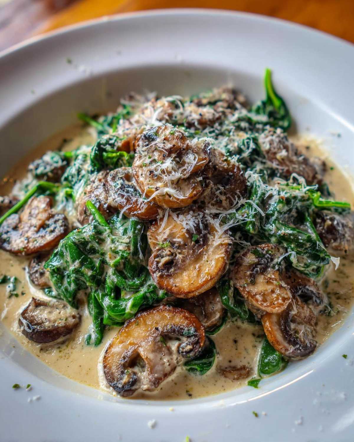 A close-up of the Keto Creamy Spinach Mushroom Skillet, featuring sautéed mushrooms and wilted spinach in a rich cream sauce, topped with grated Parmesan.