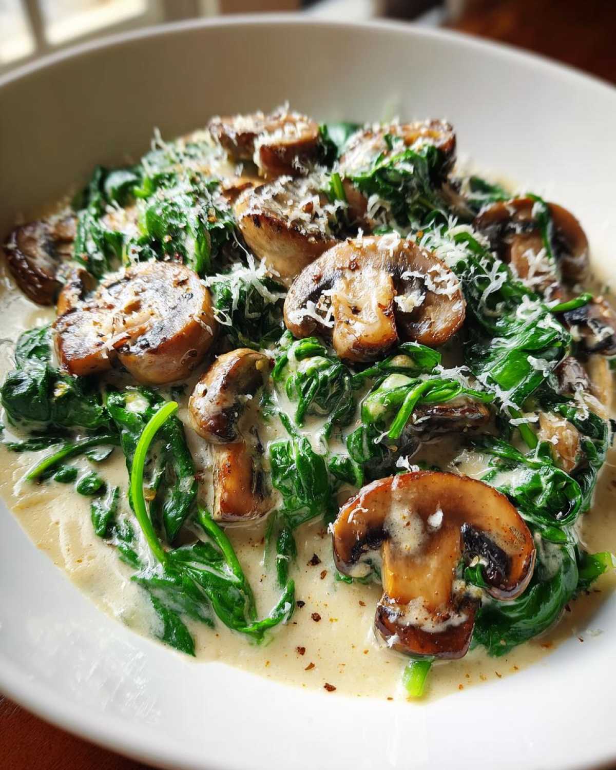 Close-up of Keto Creamy Spinach Mushroom Skillet topped with grated Parmesan cheese.