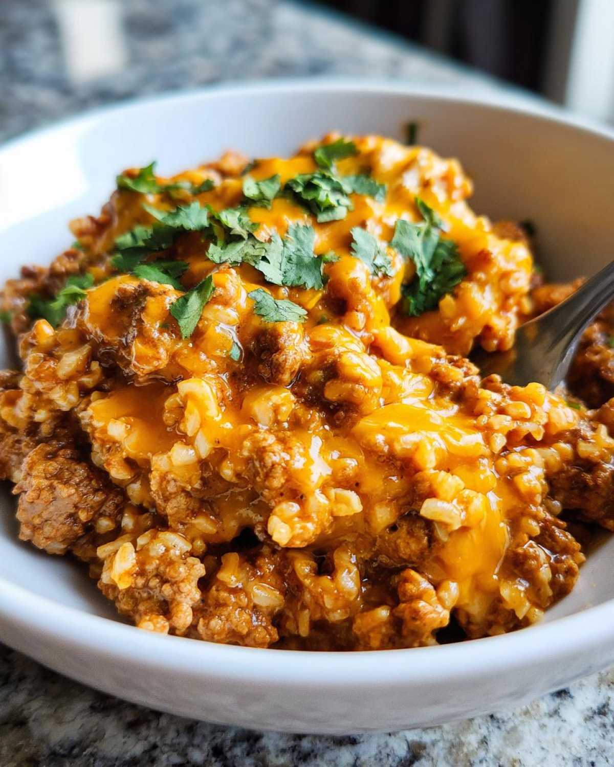 Close-up of Keto Creamy Taco Skillet with Cauliflower Rice, topped with melted cheddar cheese and fresh cilantro.