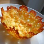 Close-up of a golden brown, lacy Keto Crispy Cheese Taco Shell Bowl resting on a white plate.