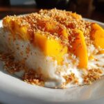 A close-up of a serving of mango sticky rice, topped with fresh mango slices and toasted sesame seeds.
