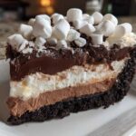Close-up of a decadent slice of Mississippi Mud Pie showing four distinct layers topped with mini marshmallows.