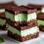 Two stacked squares of No-Bake Chocolate Mint Icebox Bars showing the chocolate crust, mint layer, and chocolate topping.