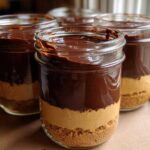 Four individual No-Bake Chocolate Peanut Butter Pie Jars layered with crust, peanut butter filling, and chocolate topping.