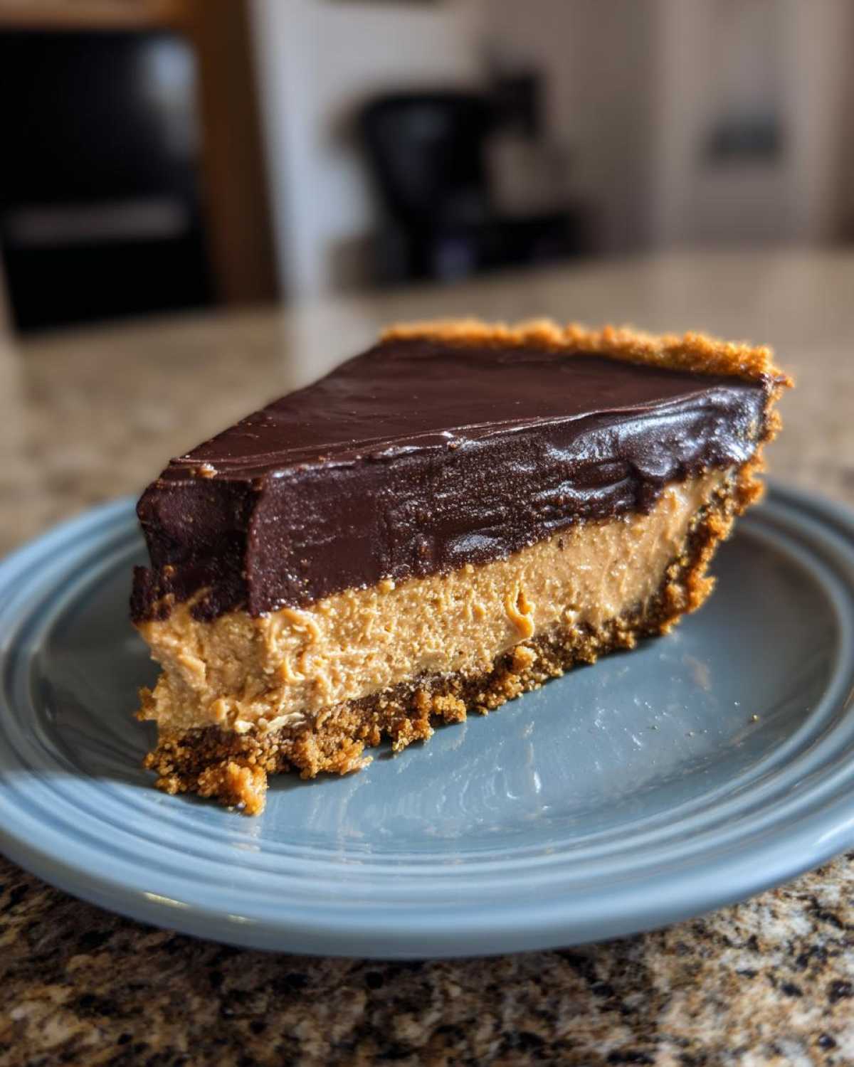 A perfect slice of no-bake chocolate peanut butter pie with a thick peanut butter layer and chocolate ganache topping.