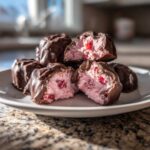 Close-up of No-Bake Chocolate Strawberry Yogurt Clusters, showing a pink, creamy interior with strawberry pieces coated in dark chocolate.