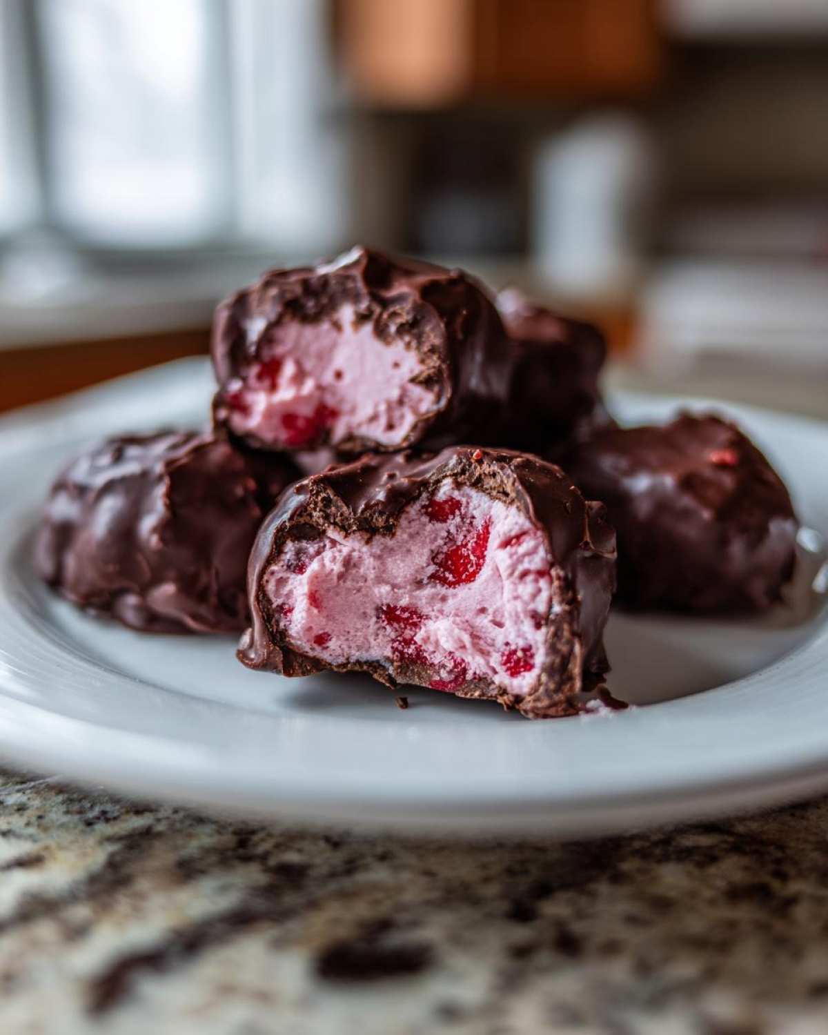 Close-up of No-Bake Chocolate Strawberry Yogurt Clusters, showing the pink yogurt filling with strawberry pieces inside dark chocolate coating.