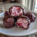 Close-up of No-Bake Chocolate Strawberry Yogurt Clusters on a white plate, showing the pink, strawberry-filled yogurt center.