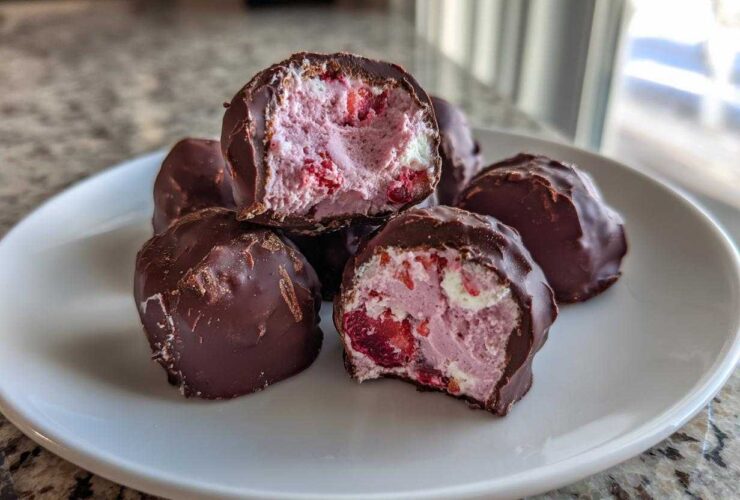 Close-up of No-Bake Chocolate Strawberry Yogurt Clusters on a white plate, showing the pink, strawberry-filled yogurt center.