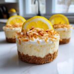 Close-up of a No-Bake Lemon Coconut Cheesecake Cup topped with toasted coconut and a lemon slice.
