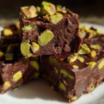 Close-up of rich, dark chocolate No-Bake Pistachio Chocolate Fudge Squares topped with bright green chopped pistachios.