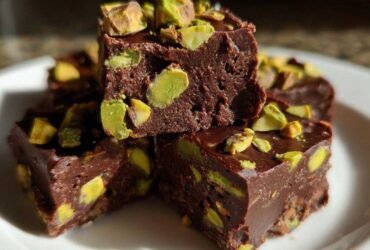 Close-up of rich, dark chocolate No-Bake Pistachio Chocolate Fudge Squares topped with bright green chopped pistachios.
