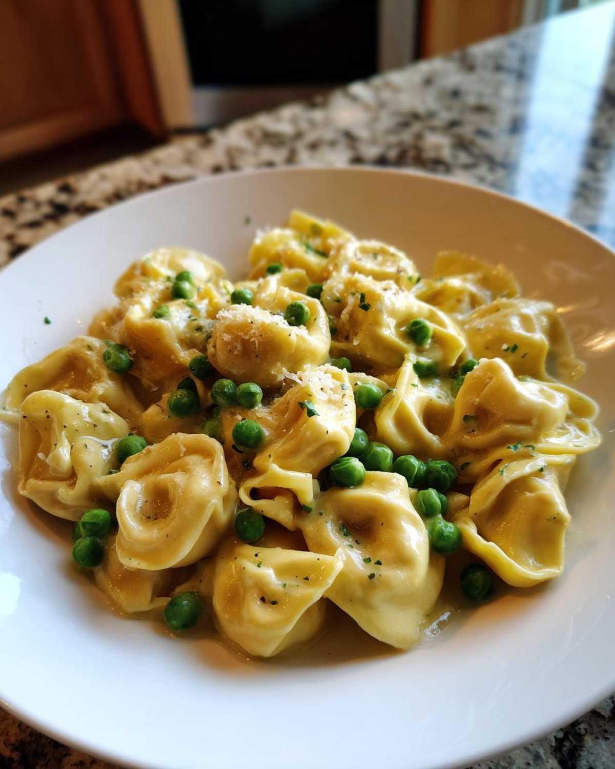 A close-up of One-Pot Creamy Garlic Butter Tortellini and Peas served in a white bowl.