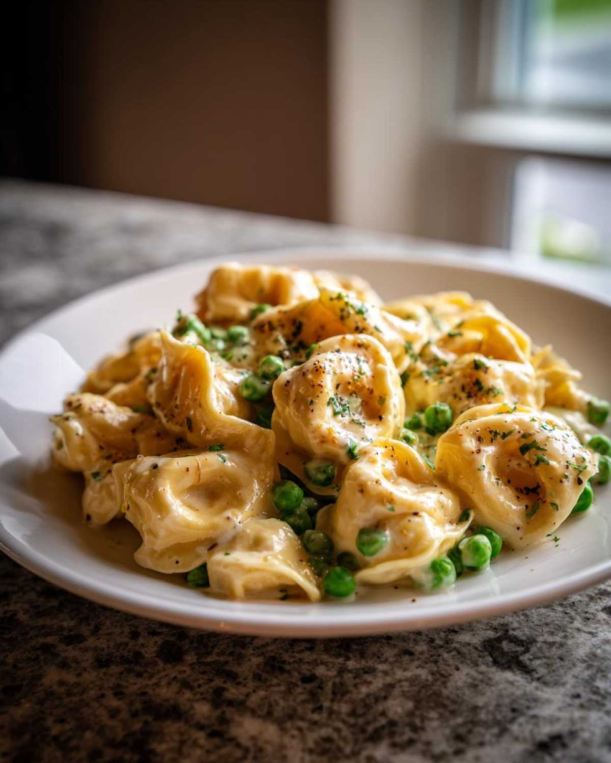 A close-up of One-Pot Creamy Garlic Butter Tortellini and Peas served on a white plate.