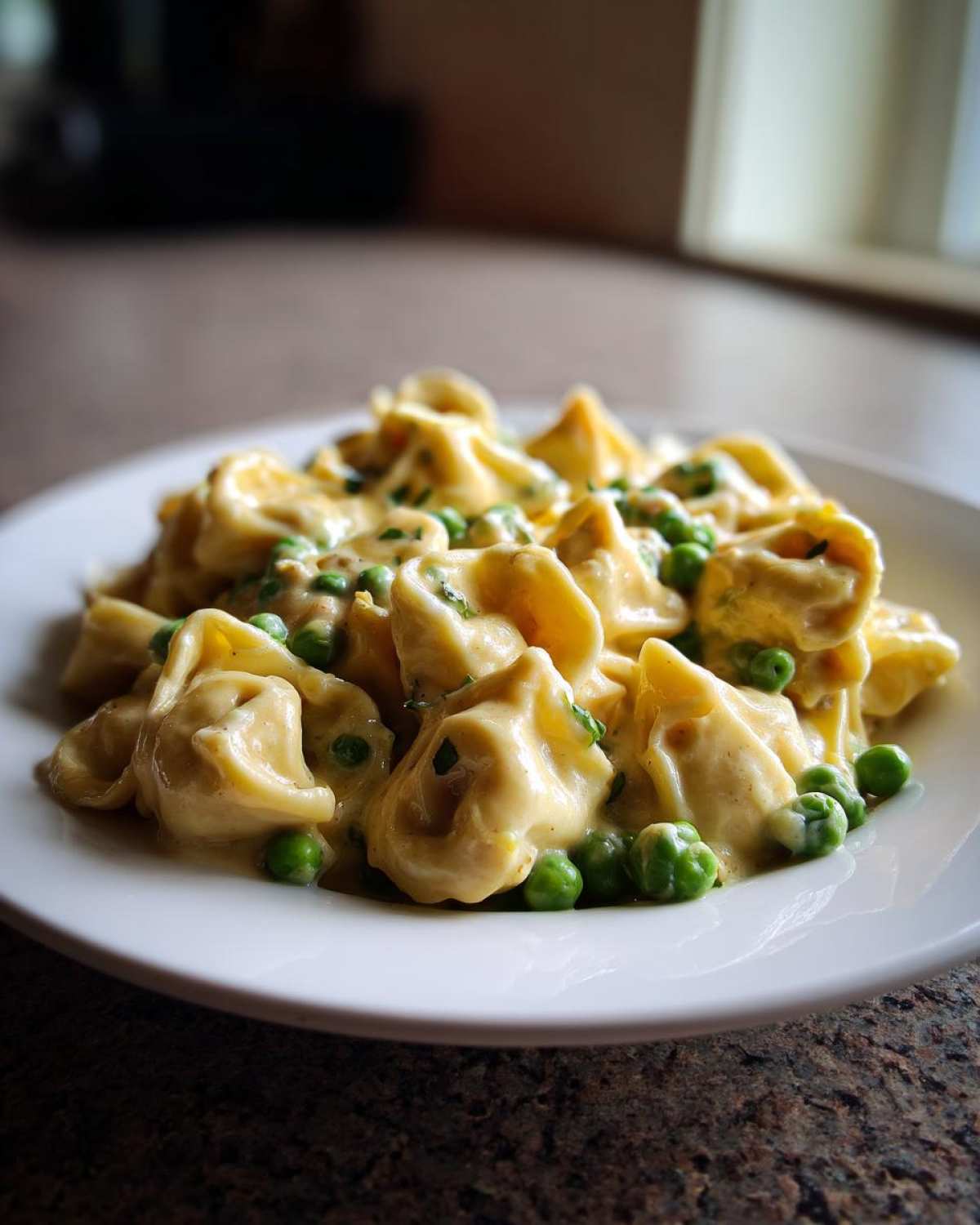 A close-up of One-Pot Creamy Garlic Butter Tortellini and Peas served on a white plate.