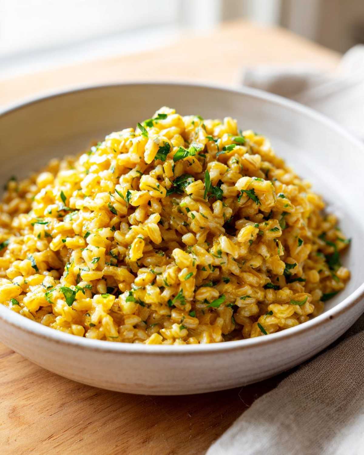 A close-up of One-Pot Creamy Lemon Garlic Farro, garnished with fresh parsley, served in a light-colored bowl.
