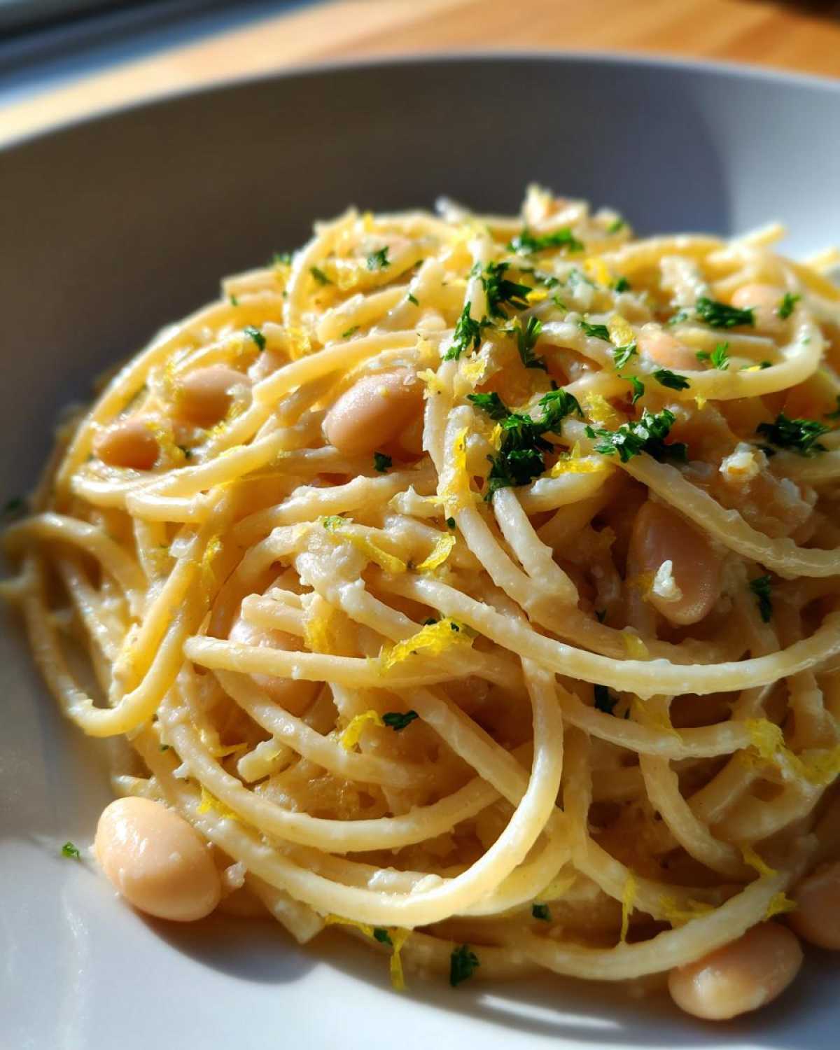 A close-up of creamy spaghetti tossed with white beans, lemon zest, and parsley, representing the One-Pot Creamy White Bean Lemon Pasta.
