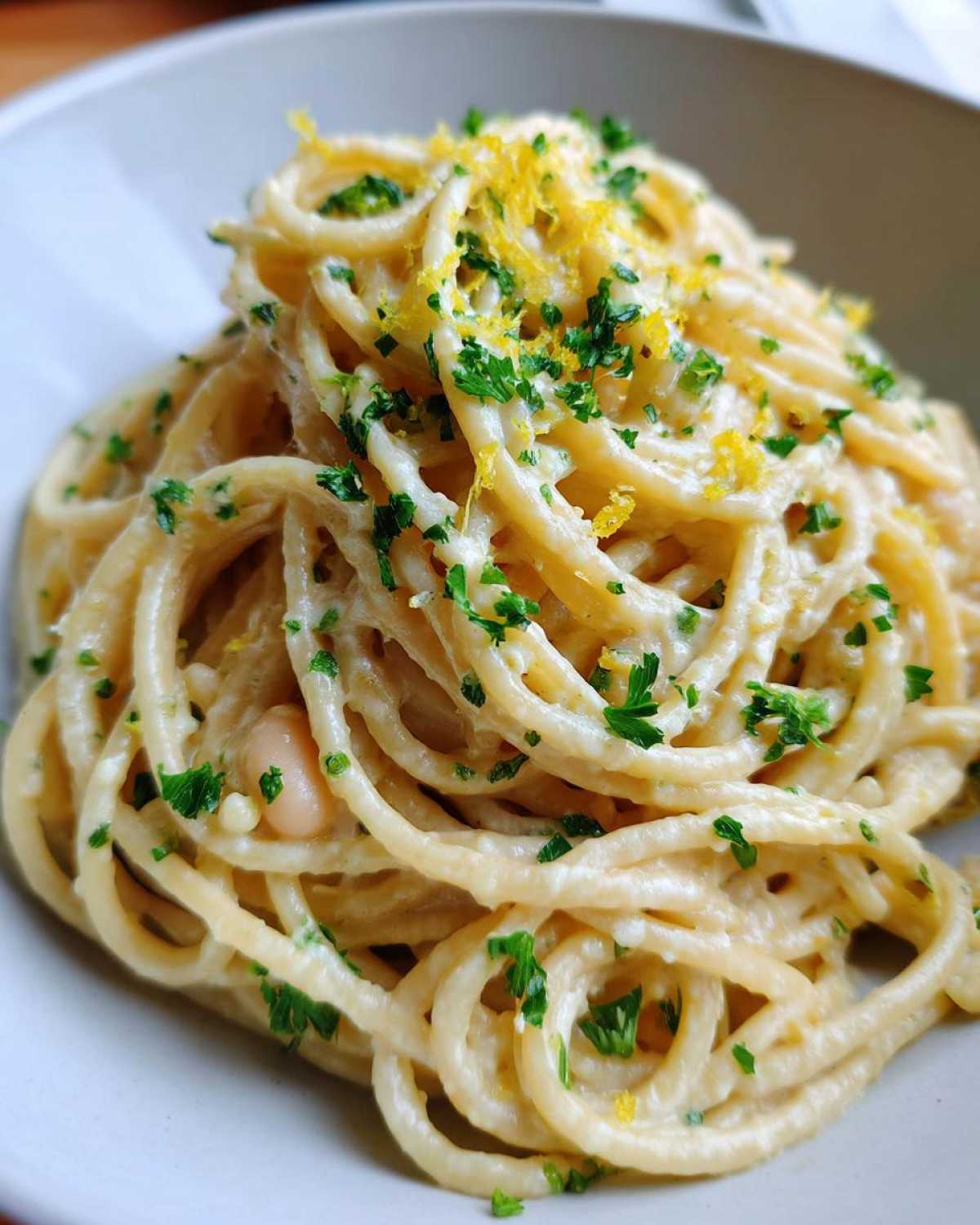 Close-up of One-Pot Creamy White Bean Lemon Pasta topped with fresh parsley and lemon zest.