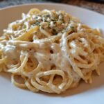 A plate of spaghetti generously coated in a rich, creamy Easy Cottage Cheese Alfredo Sauce, garnished with herbs.