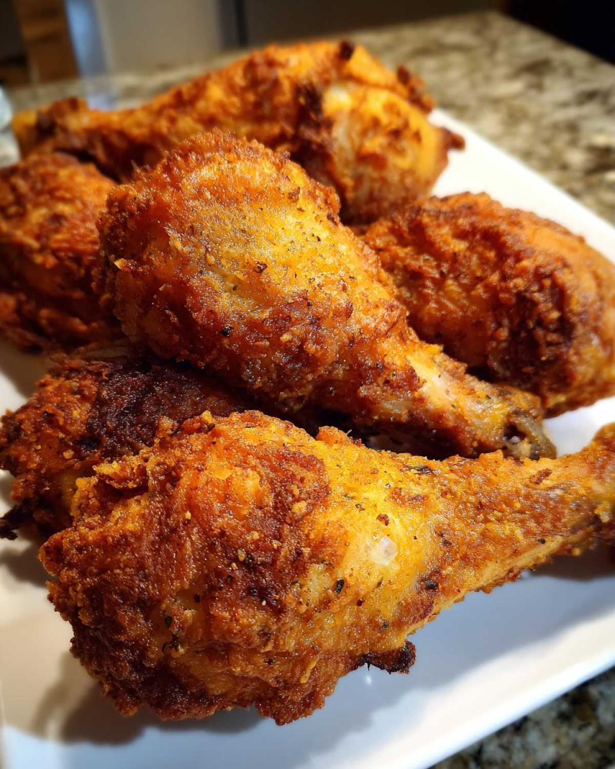 Close-up of several golden-brown, crispy Sheet Pan Crispy Ranch Chicken Drumsticks piled on a white plate.