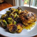 A plated serving of Sheet Pan Garlic Butter Chicken and Brussels Sprouts, featuring a glazed chicken thigh next to caramelized sprouts.