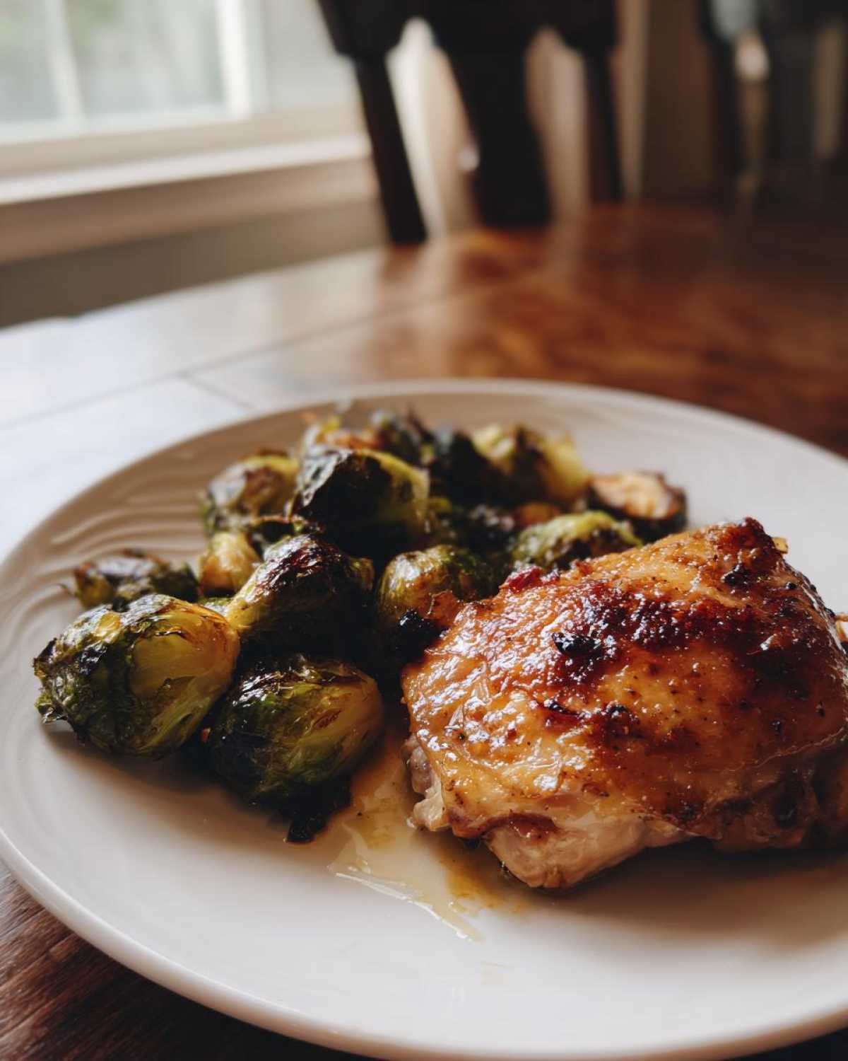 A plated serving of Sheet Pan Garlic Butter Chicken and Brussels Sprouts, featuring crispy chicken skin and roasted vegetables.