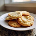 A pile of soft, golden brown cake mix cookies dusted with cinnamon sugar on a white plate.