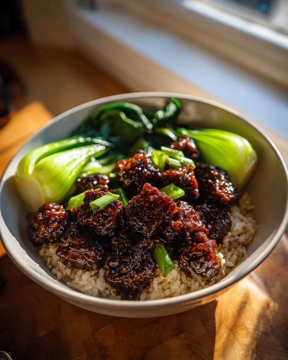 Close-up of a Vegan Crispy Sesame Tempeh Bowl served over brown rice with steamed bok choy.